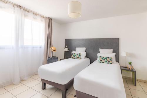 a bedroom with two beds and a window at Appart'City Confort La Ciotat - Côté Port in La Ciotat