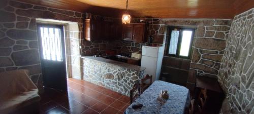 una cocina con una pared de piedra y una mesa. en Recanto da Costa, en Riba de Mouro