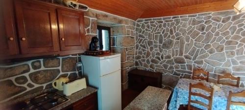 a kitchen with a stone wall and a refrigerator at Recanto da Costa in Riba de Mouro