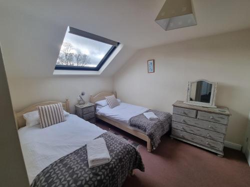 a bedroom with two beds and a tv and a window at Osprey Meadow Holiday Cottages in Bedale