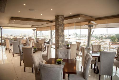 a restaurant with tables and chairs and windows at Hotel Fundador by Robles in Arequipa