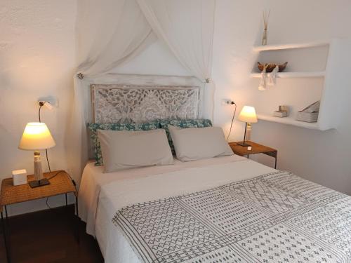a bedroom with a large white bed with two lamps at wonderful sunsets views from terraces Last minute in Cala Vadella