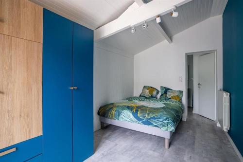 une chambre avec un lit et un mur bleu dans l'établissement Maison de vacances Bisca, à Biscarrosse