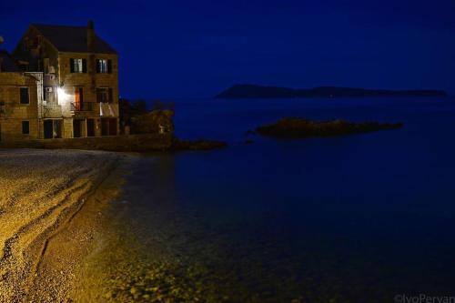 a building on the shore of the water at night at Villa Kuljis in Komiža