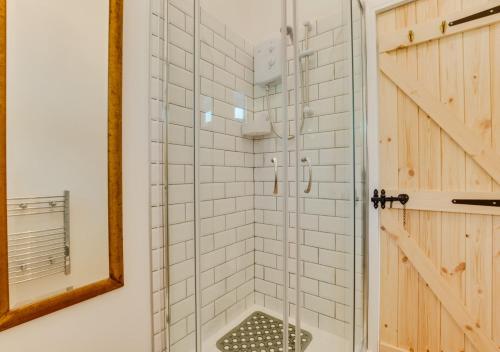 een douche met een glazen deur in de badkamer bij The Trefanny Inn in Duloe