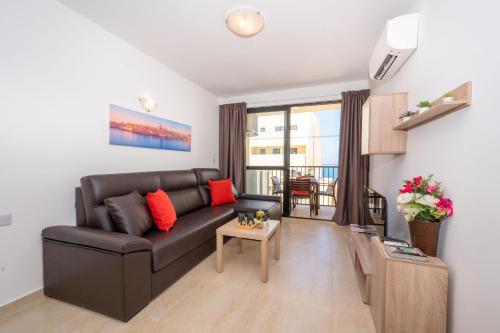 a living room with a black leather couch and a table at Sea Bliss Apartments with terrace just off seafront in St Paul's Bay - By Getawaysmalta in St. Paul's Bay