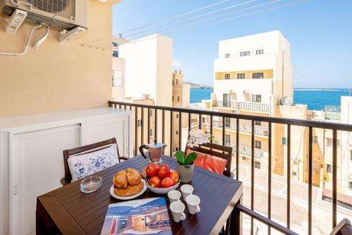 una mesa con un plato de comida en el balcón en Sea Bliss Apartments with terrace just off seafront in St Paul's Bay - By Getawaysmalta, en St Paul's Bay