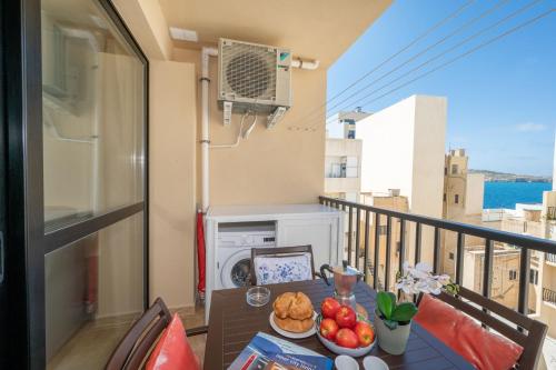 a table with a plate of food on a balcony at Sea Bliss Apartments with terrace just off seafront in St Paul's Bay - By Getawaysmalta in St. Paul's Bay