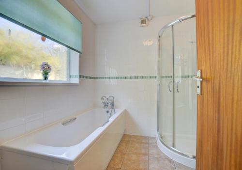La salle de bains est pourvue d'une baignoire et d'une douche en verre. dans l'établissement High Tides, à Crafthole
