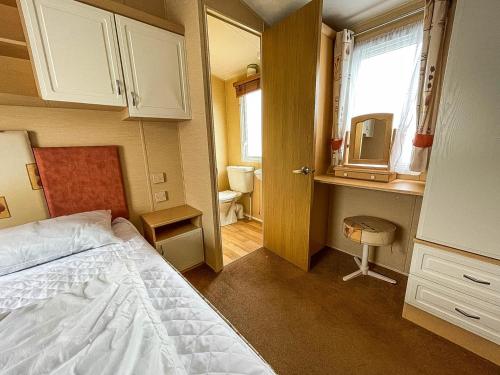 1 dormitorio con cama y baño con espejo. en Great 6 Berth Caravan With Decking By The Beach In Suffolk Ref 40023nd en Lowestoft