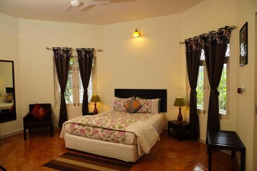 a bedroom with a bed and two windows at Copperhill- A Luxury Homestay in Madikeri
