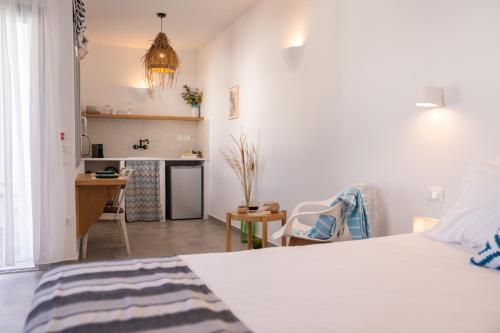 a white bedroom with a bed and a kitchen at Ammos Sifnos Village in Platis Yialos Sifnos