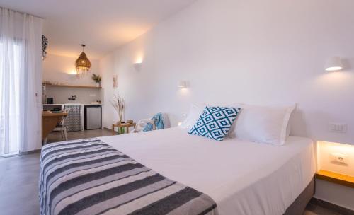 a bedroom with a large white bed and a kitchen at Ammos Sifnos Village in Platis Yialos Sifnos