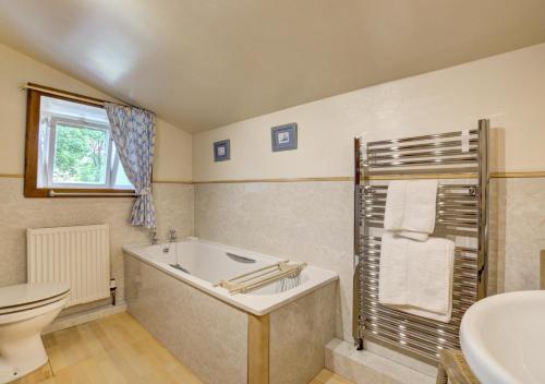 y baño con bañera, aseo y lavamanos. en West Cottage en Thwaite