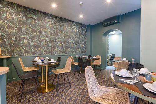 a dining room with tables and chairs and a wall mural at Hotel De Paris in Boulogne-Billancourt