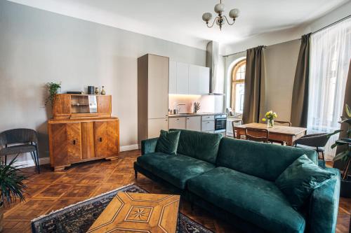 a living room with a green couch and a kitchen at Constantine Apartments in Riga