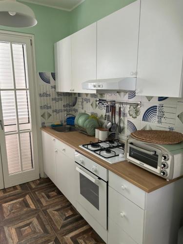 uma cozinha com armários brancos, um fogão e um micro-ondas em Casa Vacanza e B&B em Amica