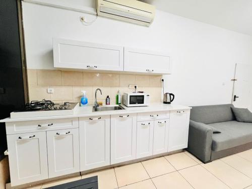 a kitchen with a sink and a microwave and a couch at New! Royal family ground apartment 2BR in Bat Yam