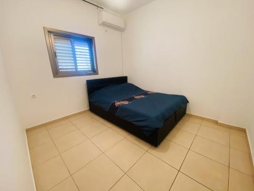 a small bedroom with a bed in a room with a window at New! Royal family ground apartment 2BR in Bat Yam
