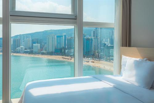 een slaapkamer met een groot raam met uitzicht op het strand bij Hotel Marine view in Busan