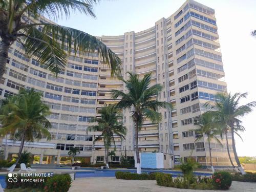 a large building with palm trees in front of it at Ocean Blue in Porlamar