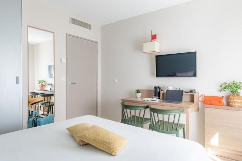 a bedroom with a bed and a desk with a computer at Appart'City Classic Valence in Valence