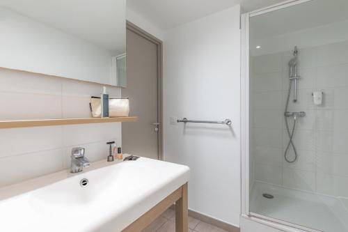 La salle de bains blanche est pourvue d'un lavabo et d'une douche. dans l'établissement Appart'City Classic Valence, à Valence