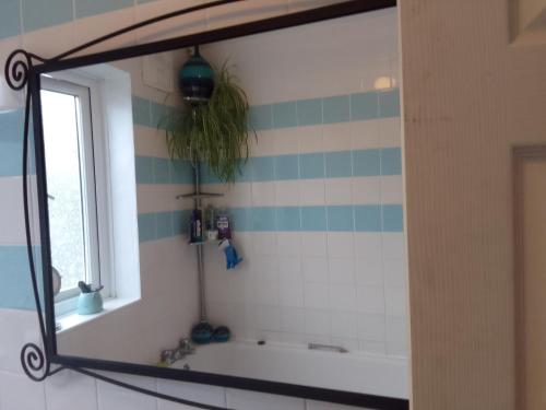 espejo en el baño con bañera y ventana en Rose's Home en Streatham