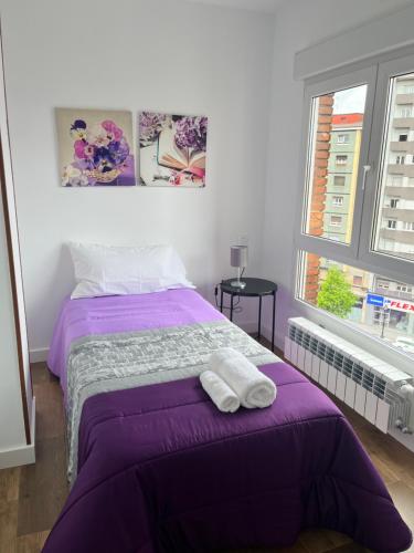 a bedroom with a purple bed with two towels on it at Tía Ana in Gijón