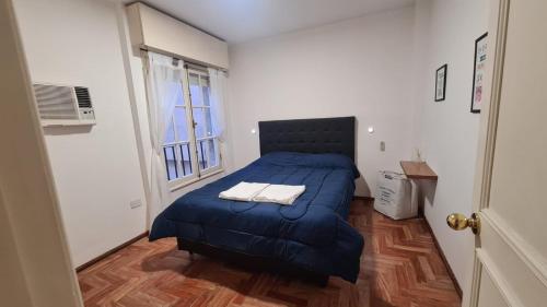 Un dormitorio con una cama azul y una ventana en Balcones del Este en Córdoba