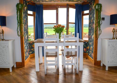a white dining room table with white chairs and a window at The Tower, Moray Firth Holiday Home in Kinloss