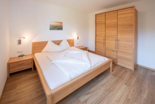 a bedroom with a large white bed and wooden cabinets at Feltonhof in Cornaiano