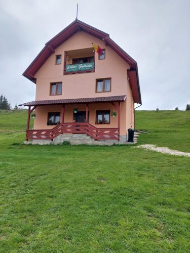 a house on top of a grassy field at Cabana Gabriela in Gîrda de Sus