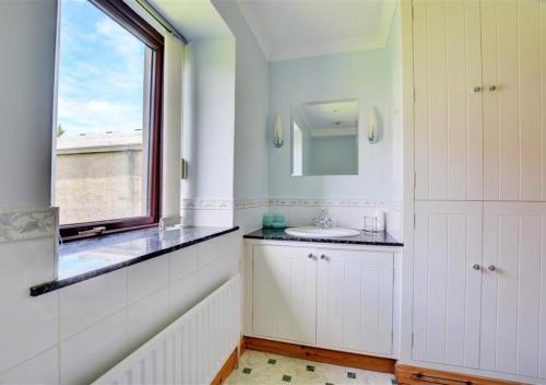a white bathroom with a sink and a window at Weavers Loft in Cowling