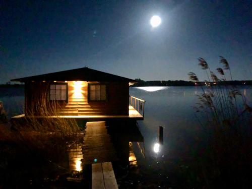 eine Hütte auf einem Dock im Wasser in der Nacht in der Unterkunft Piękny Dom na wodzie!!! Mazury szlak WJM in Ryn