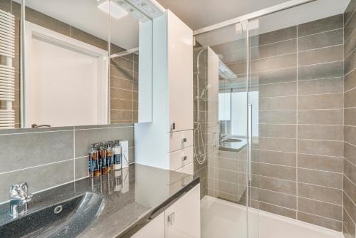 een badkamer met een wastafel en een douche bij maison des dunes in Oostende