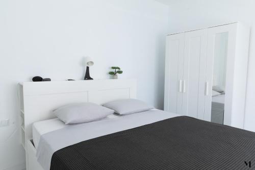 a white bedroom with a bed with two pillows at Aqua Vista Playa San Juan in Playa de San Juan