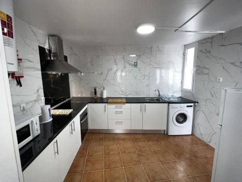 a kitchen with white cabinets and a stone wall at Studio Home Away from Home in Caniçal