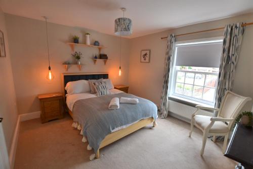 um quarto com uma cama, uma janela e uma cadeira em The Old Tailors Cottage em Long Whatton