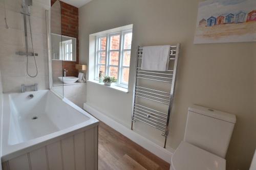 uma casa de banho branca com um lavatório e um WC em The Old Tailors Cottage em Long Whatton