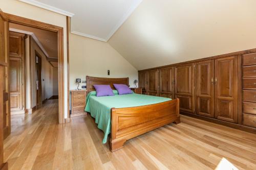 1 dormitorio con 1 cama con almohadas moradas y armarios de madera en El Pongallin ideal para familias, en Sevares