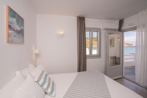 a bedroom with a white bed with a view of the ocean at Ammos Sifnos Village in Platis Yialos Sifnos
