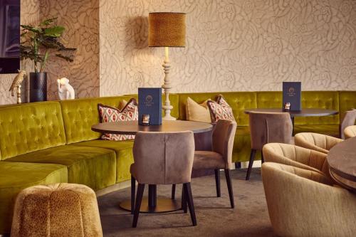 a restaurant with a green couch and tables and chairs at Van der Valk Palace Hotel Noordwijk in Noordwijk aan Zee