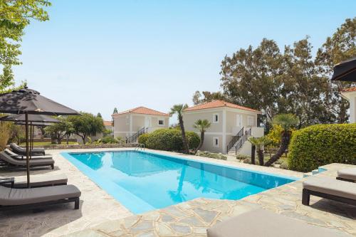 a swimming pool with two chairs and an umbrella at Doryssa Coast Apartments in Pythagoreio