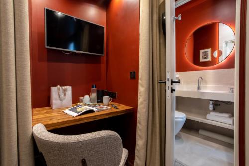 łazienka z biurkiem, toaletą i telewizorem w obiekcie Hotel Sacha w Paryżu