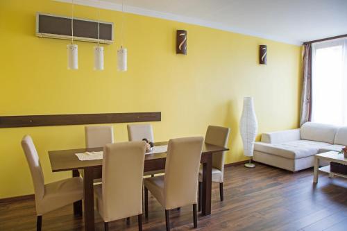 a dining room with a table and chairs and a couch at Golden apartman in Gyula