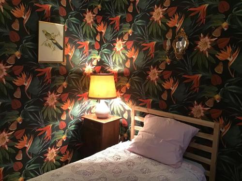 a bedroom with a floral wallpaper with a bed and a lamp at Chambres d Hôtes Les Filles Tresy in Passenans