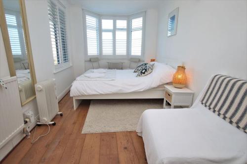 a bedroom with two beds and two windows at The Cabin at Gabriel House in Ilfracombe