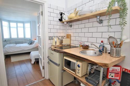 a small kitchen with a sink and a bedroom at The Cabin at Gabriel House in Ilfracombe