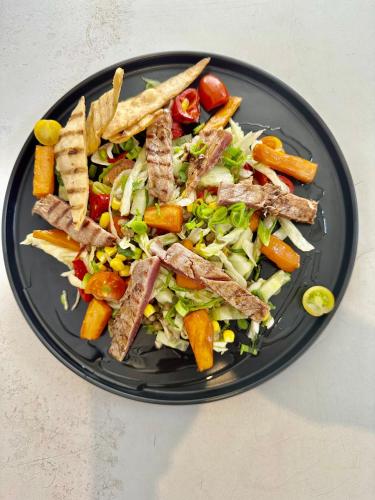 a black plate with a salad with meat and fries at Boutique Citadel in Eforie Nord